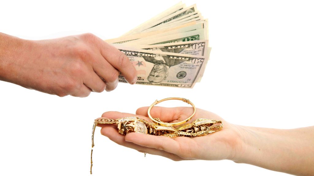 A hand holding a dollar note and a gold bar, symbolizing exchange.