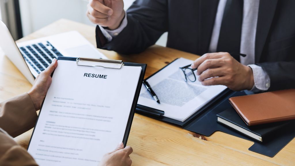 A handwritten notepad with the phrase "clear and concise language," emphasizing the importance of professional resume writing.